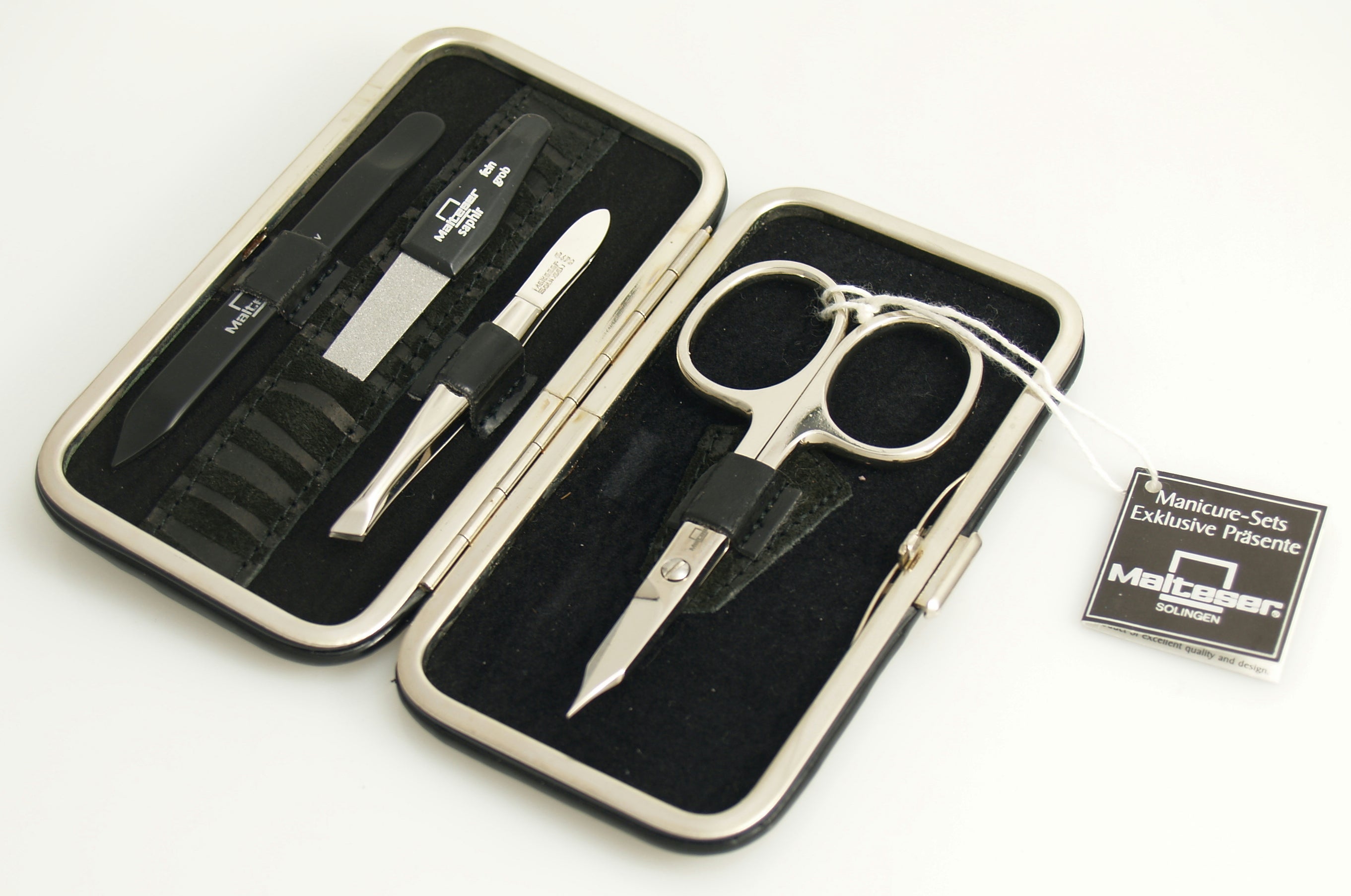 Malteser manicure set with four black lacquer and velvet leather steel tools, compact and stylish for grooming.