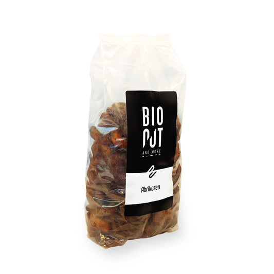 Bionut organic apricots in a 1kg bag, fresh and ripe, placed on a wooden surface with some apricots cut open showing the flesh.