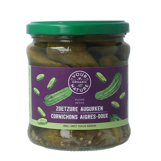 Jar of Your Organic Nature sweet and sour pickled cucumbers in 330g, with fresh vegetables and fruits in the background.