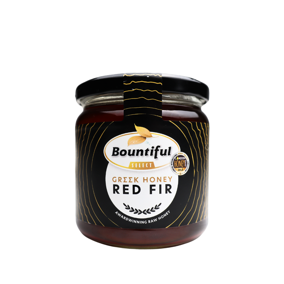 Bountiful Select Griekse rauwe honing met rode spar, 500 gram, close-up of jar with golden honey and red fir tree in background.