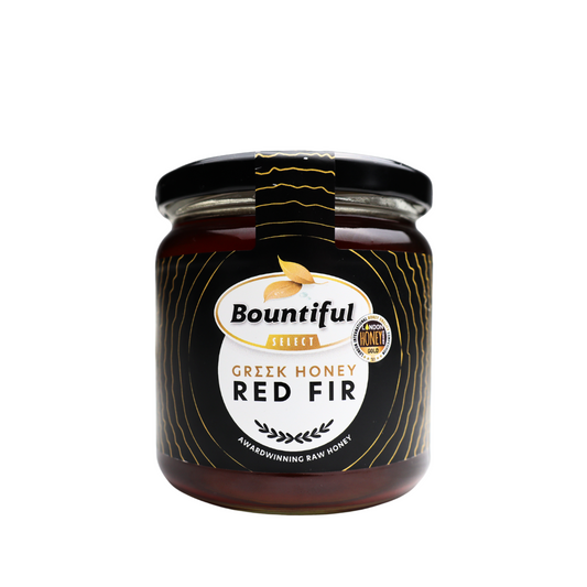 Bountiful Select Griekse rauwe honing met rode spar, 500 gram, close-up of jar with golden honey and red fir tree in background.