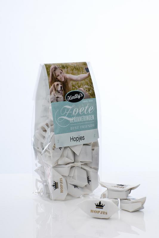Kindly's Hollandse hopjes snoepgoed in 130g package, showing golden caramel candies with a smooth, glossy texture.