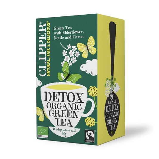 Clipper Detox green tea bio tea bags, eco-friendly packaging, fresh green leaves, and tea infuser, in a natural setting.