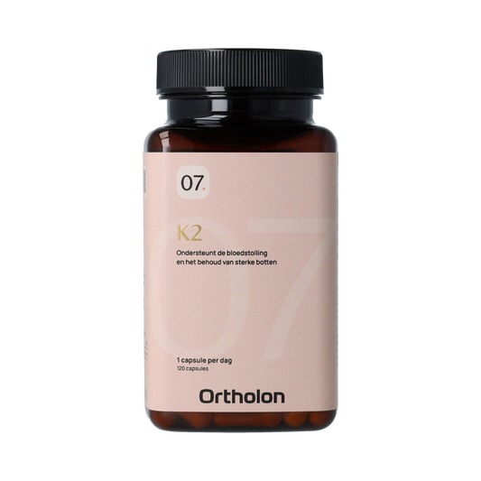 Ortholon Vitamin K2 capsules in a bottle, supplement for bone and cardiovascular health, shown in a natural setting